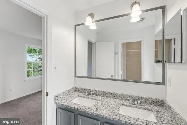 a bathroom with a granite countertop sink and a mirror