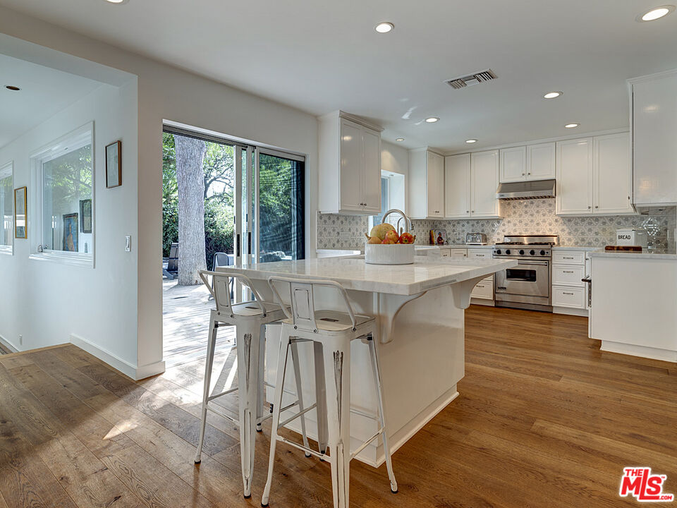 1314 Preston Way Venice, CA 90291 - Photo 10 of 30 a kitchen with stainless steel appliances granite countertop a stove top oven a sink dishwasher a dining table and chairs with wooden floor