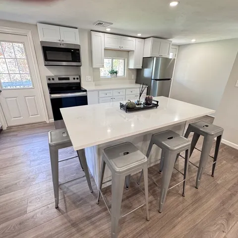 a kitchen with a table chairs refrigerator and window
