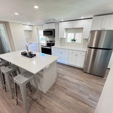 a kitchen with stainless steel appliances a kitchen island hardwood floor sink and stove