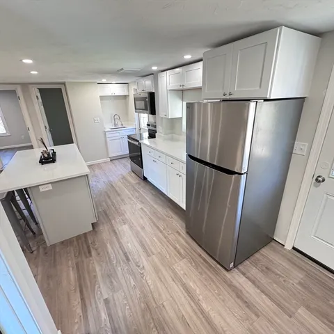 a kitchen with stainless steel appliances a refrigerator sink and wooden floor