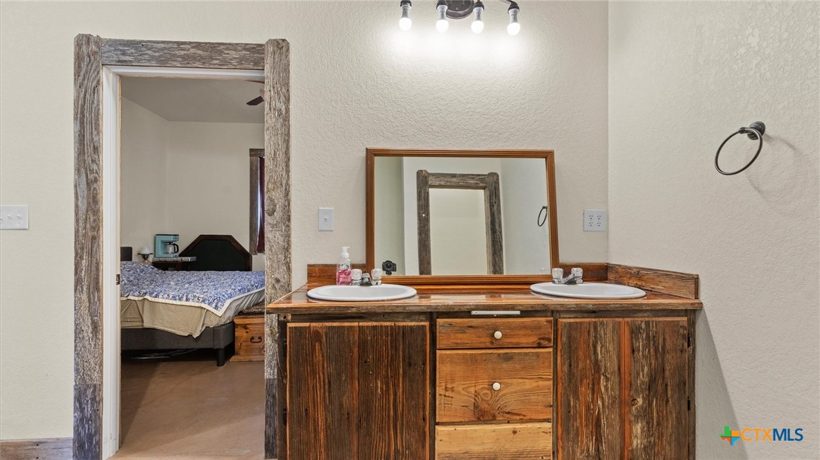 707 Creek Road Marion, TX 78124 - Photo 11 of 32 a en suite bathroom with a granite countertop sink and a mirror