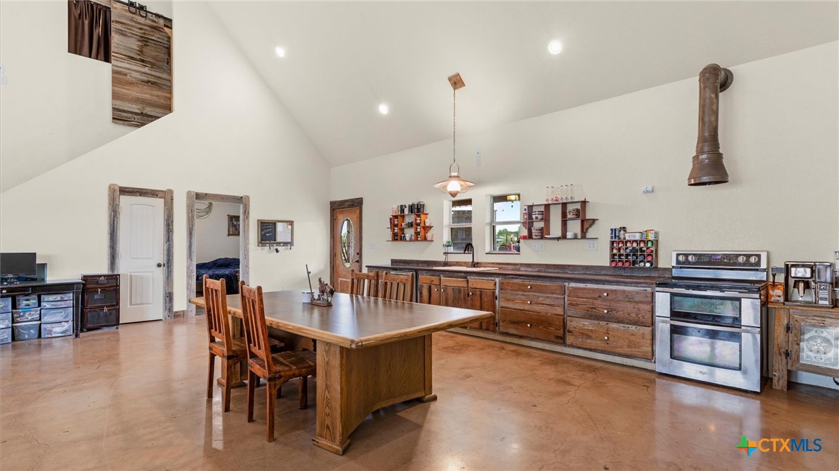 707 Creek Road Marion, TX 78124 - Photo 4 of 32 a kitchen with stainless steel appliances granite countertop a stove a sink a dining table and chairs with wooden floor
