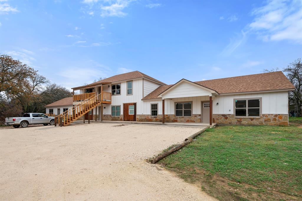2877 Conveyor Drive, Unit B Burleson, TX 76028 - Photo 1 of 22 View of front of house featuring stone siding, a shingled roof, stairway, a front lawn, and board and batten siding