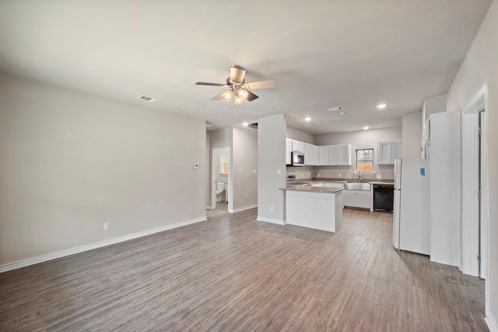 2877 Conveyor Drive, Unit B Burleson, TX 76028 - Photo 22 of 22 Kitchen featuring appliances with stainless steel finishes, open floor plan, light wood finished floors, a ceiling fan, and white cabinetry