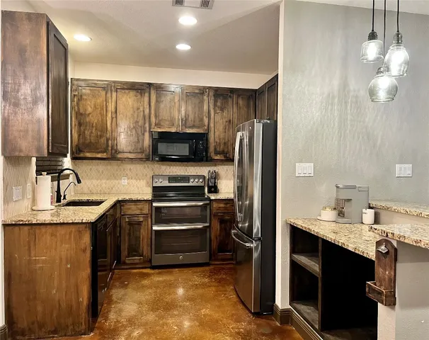 a kitchen with kitchen island granite countertop a refrigerator and a sink