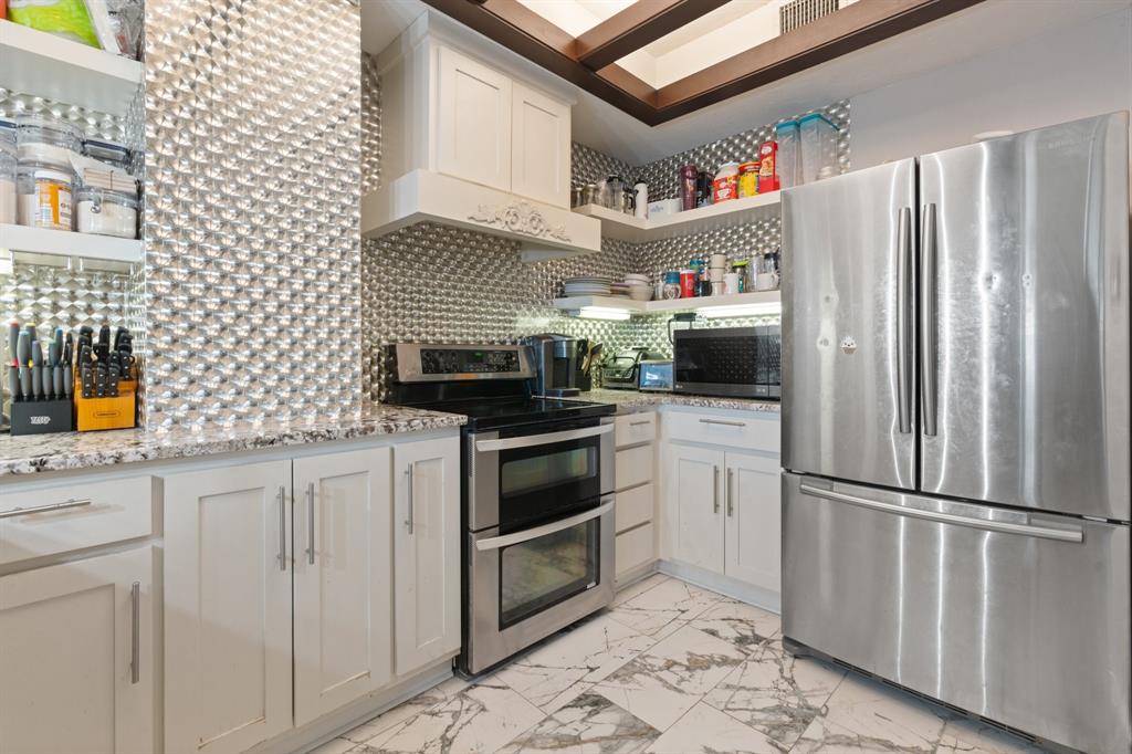 2100 Reflection Bay Drive Arlington, TX 76013 - Photo 4 of 20 a kitchen with stainless steel appliances a refrigerator a sink and wooden cabinets