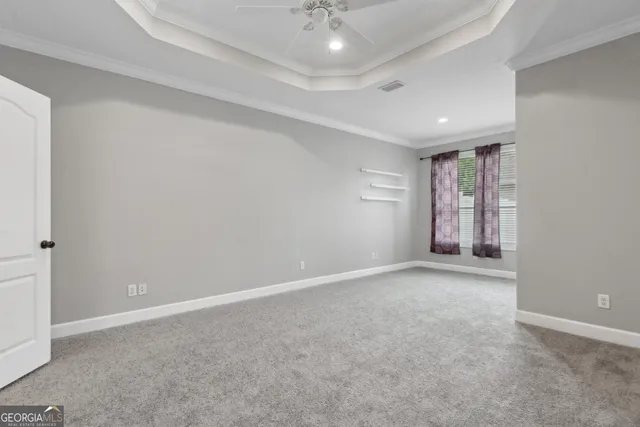 an empty room with windows and chandelier fan
