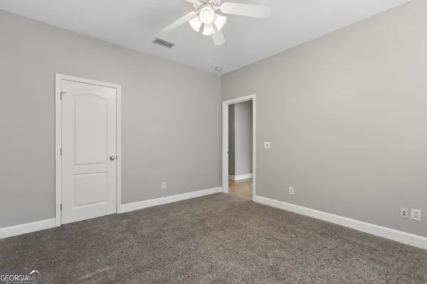an empty room with a chandelier fan and closet area