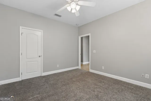 an empty room with a chandelier fan and closet area