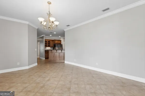 a view of a livingroom with a chandelier fan and kitchen view