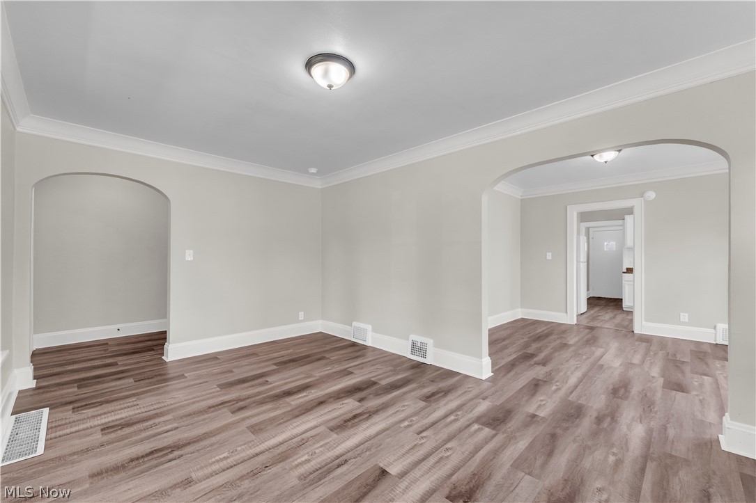 18123 McCracken Road Maple Heights, OH 44137 - Photo 6 of 27 Spacious room featuring wood-finish flooring, light neutral wall tones, crown molding, and two arched doorways