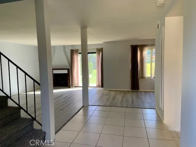 an empty room with wooden floor fireplace and windows
