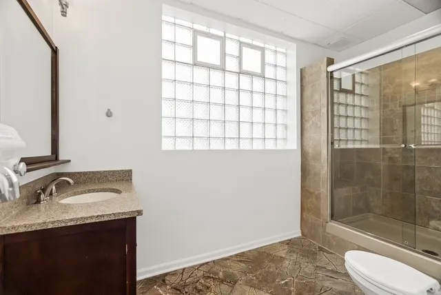 a bathroom with a granite countertop sink toilet and shower