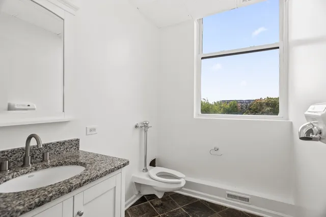 a bathroom with a granite countertop sink mirror vanity and toilet