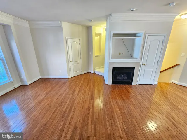 a view of empty room with wooden floor and fireplace
