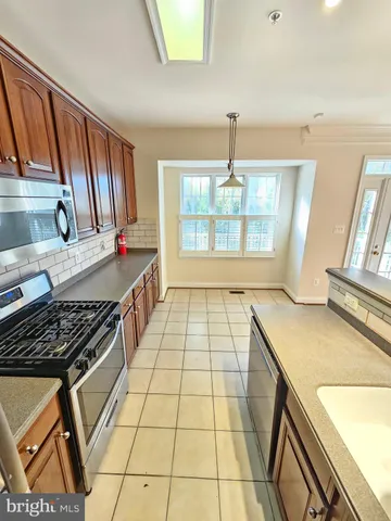 a kitchen with a stove a sink a refrigerator and wooden floor