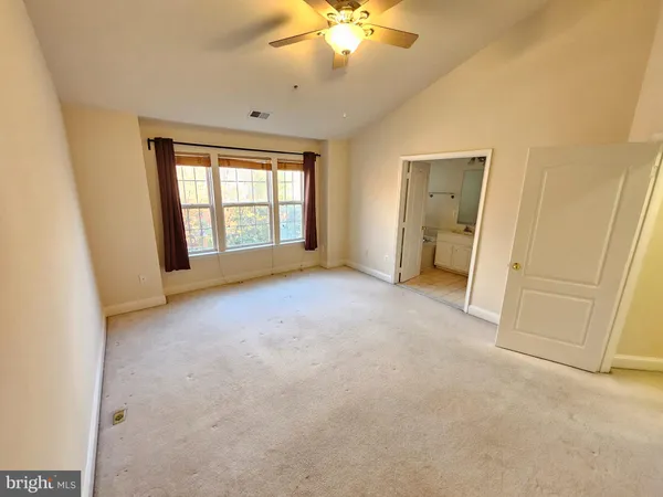 an empty room with windows and fan