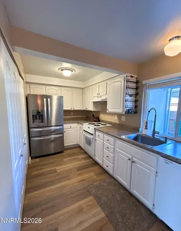 a large kitchen with cabinets a sink and stainless steel appliances