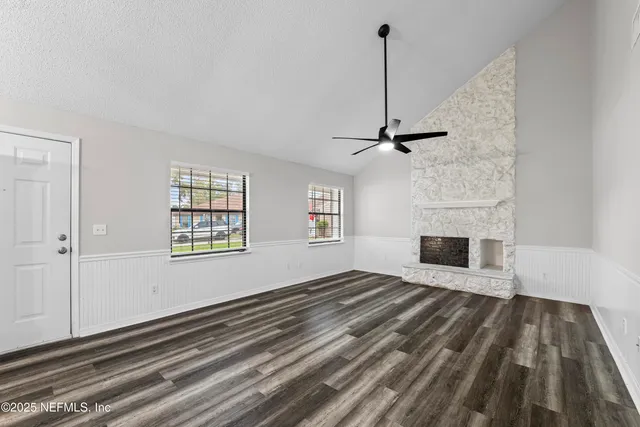 a view of an empty room with wooden floor fireplace and a window