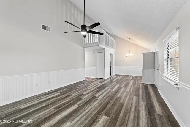 a view of empty room with wooden floor and fan