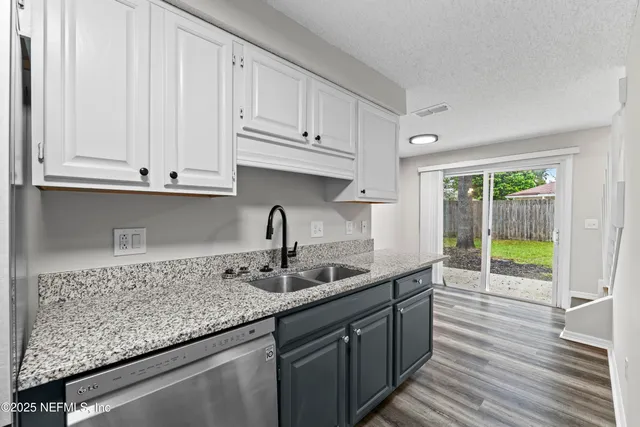 a kitchen with granite countertop a sink a stove and cabinets