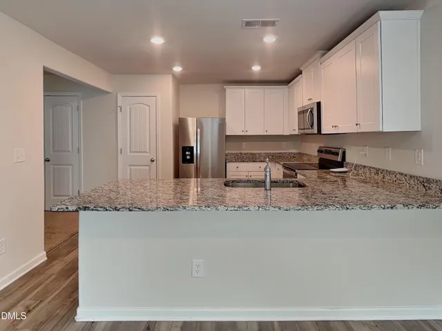 a kitchen with stainless steel appliances granite countertop a sink a stove and a refrigerator