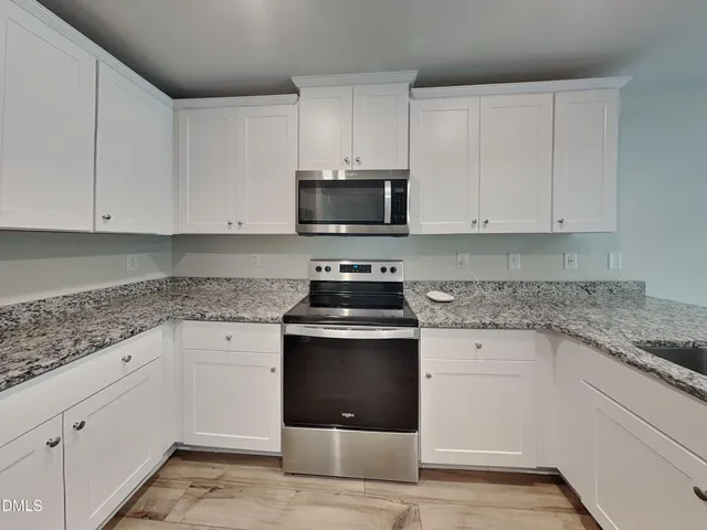 a kitchen with granite countertop white cabinets and stainless steel appliances