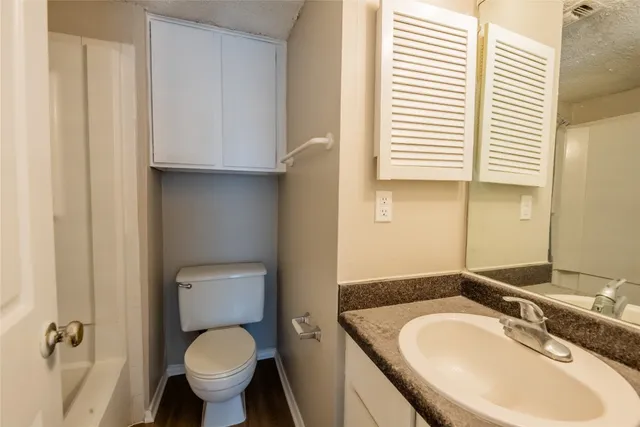 a bathroom with a granite countertop toilet and a sink