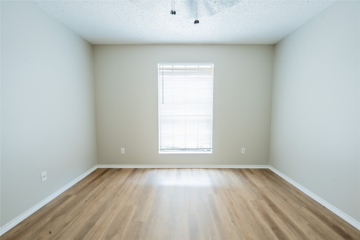 2401 Leon Street, Unit 108 Austin, TX 78705 - Photo 8 of 13 an empty room with wooden floor and windows