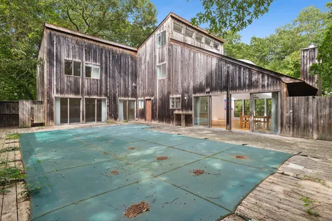 a backyard of a house with large trees and wooden fence