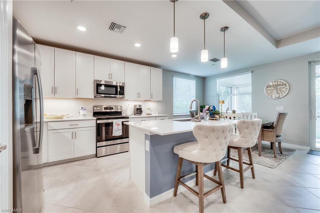 3790 Pebblebrook Ridge Court, Unit 101 Fort Myers, FL 33905 - Photo 13 of 38 a kitchen with stainless steel appliances granite countertop a sink a stove a refrigerator cabinets and a dining table with chairs