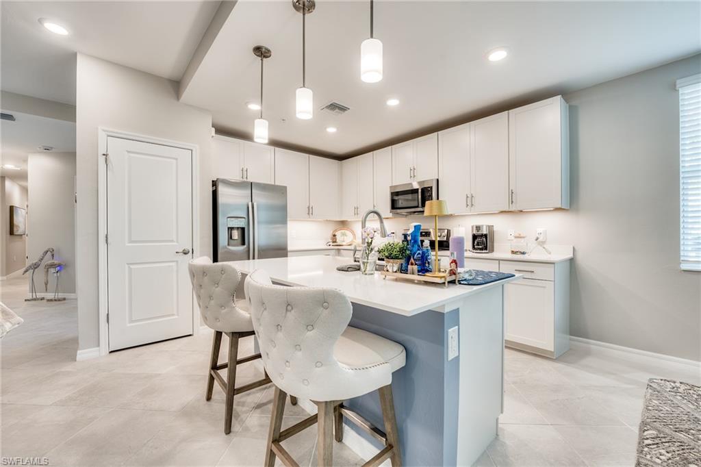 3790 Pebblebrook Ridge Court, Unit 101 Fort Myers, FL 33905 - Photo 14 of 38 a kitchen with stainless steel appliances granite countertop a sink a stove a refrigerator cabinets and chairs