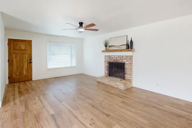 an empty room with wooden floor fireplace and windows