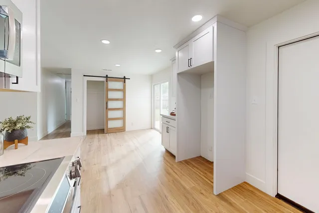 a view of an empty room with wooden floor and a bathroom