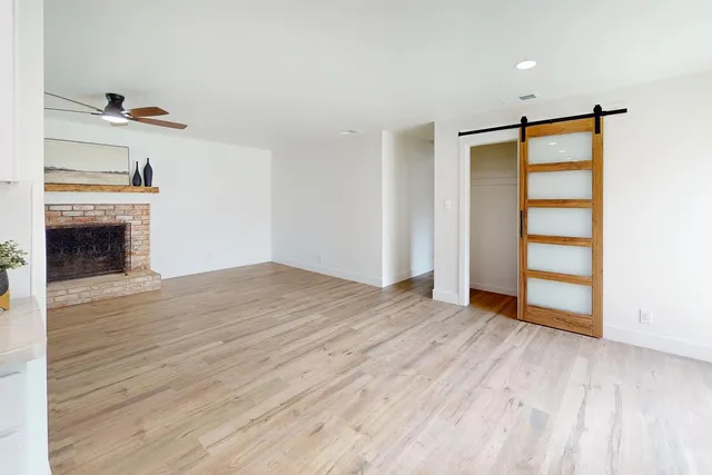 an empty room with wooden floor fireplace and windows
