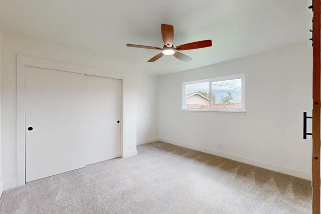 an empty room with windows and fan