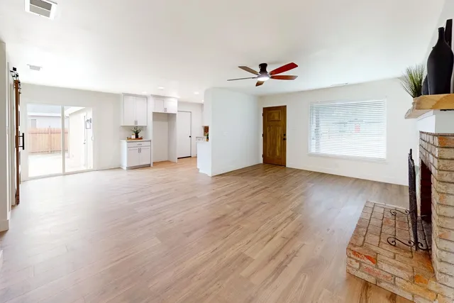 a view of an empty room with window and wooden floor