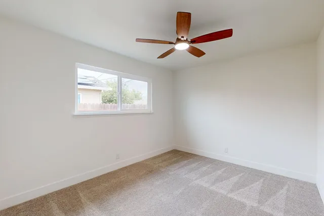 an empty room with a window and a ceiling fan
