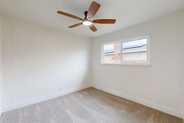 an empty room with a window and a ceiling fan