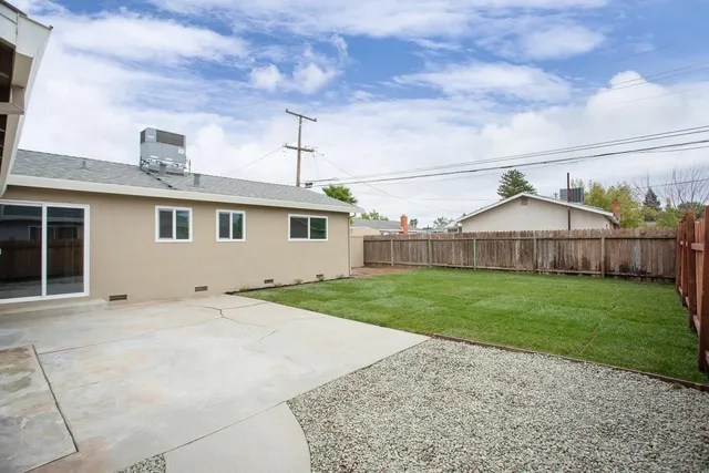 a backyard of a house with wooden fence and a bench