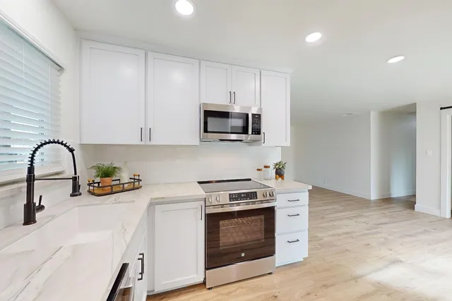 a kitchen with stainless steel appliances a stove a microwave and a sink