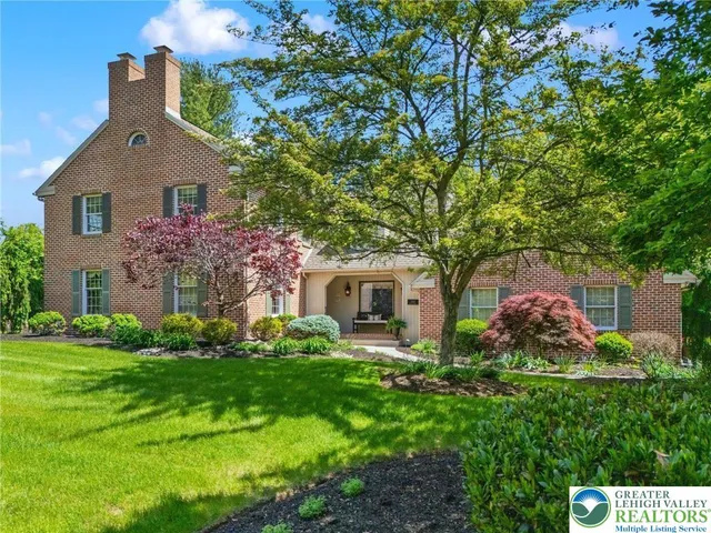 a view of a house with a yard plants and large tree