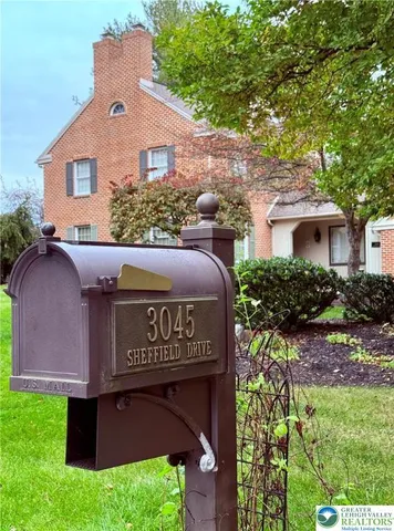 a view of a white house next to a yard with big trees