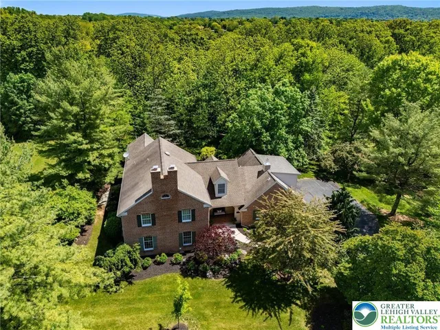an aerial view of a house with a yard and large trees