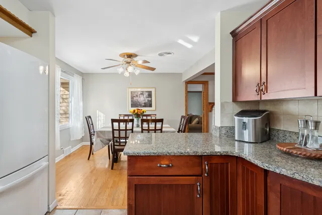 a kitchen with granite countertop a sink dishwasher a dining table and chairs with wooden floor