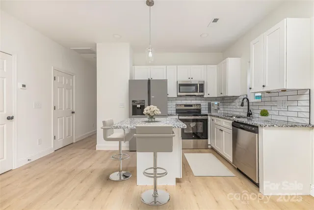 a kitchen with kitchen island granite countertop a sink cabinets and stainless steel appliances