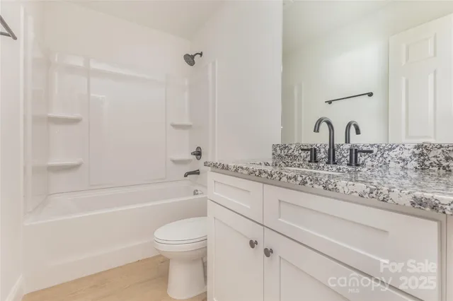 a bathroom with a granite countertop toilet a sink and bathtub