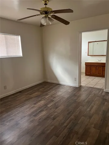 an empty room with wooden floor cabinet and windows