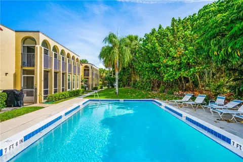 a view of swimming pool with lawn chairs and plants
